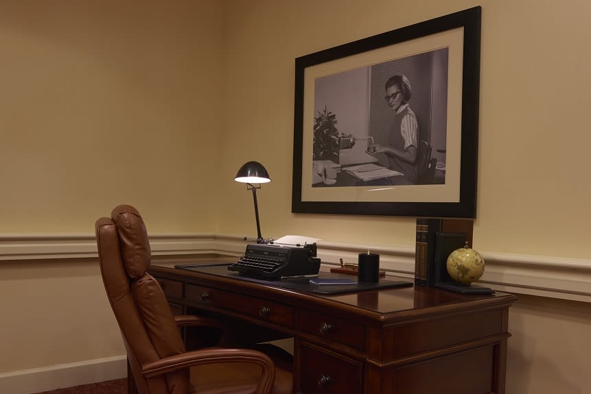 A cozy office setup with a wooden desk, leather chair, and framed photograph.