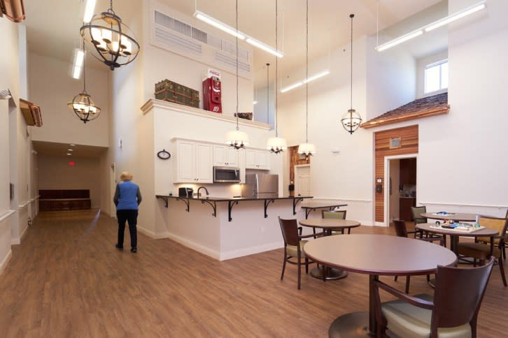 A spacious cafe with high ceilings, chandeliers, and a cozy atmosphere featuring wooden floors and comfortable seating.