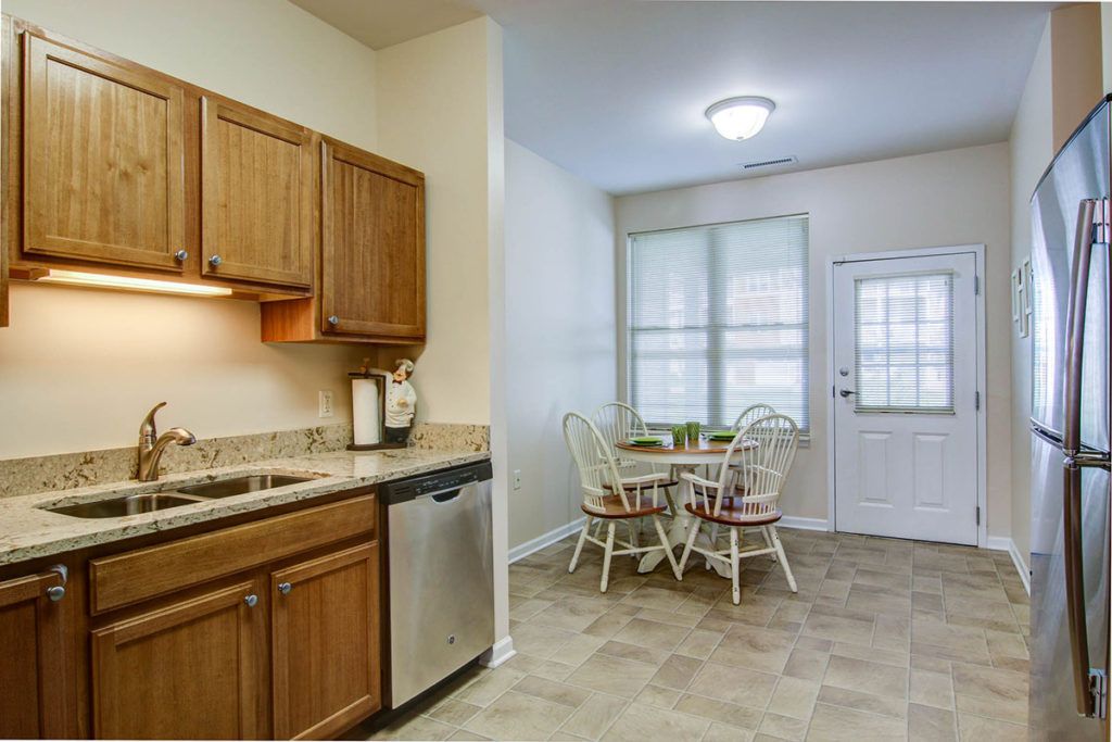 A cozy kitchen with wooden cabinets, a small dining table, and a dishwasher.