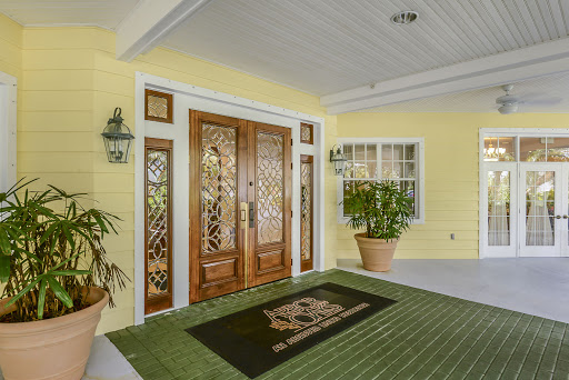 A welcoming entrance with elegant wooden doors and vibrant yellow walls, adorned with greenery.
