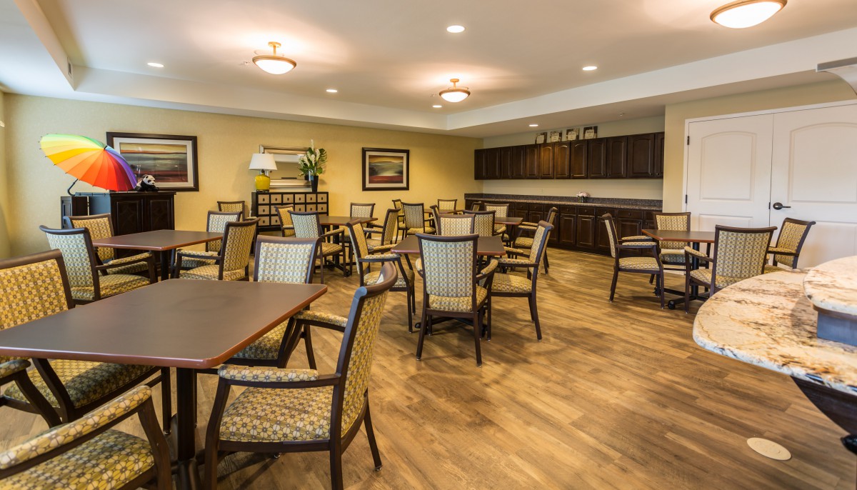 An empty dining area with neatly arranged tables and chairs on a wooden floor.