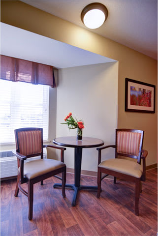 A cozy corner with a round table and two chairs, decorated with fresh flowers near a window.