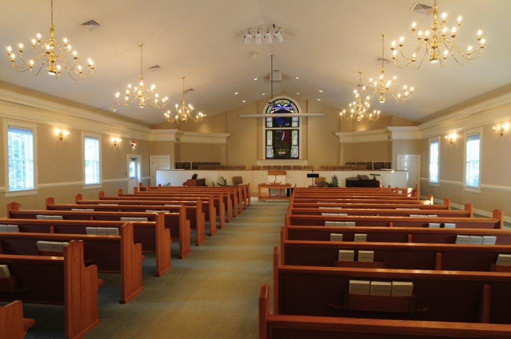 Interior view of a church with wooden pews and chandeliers.