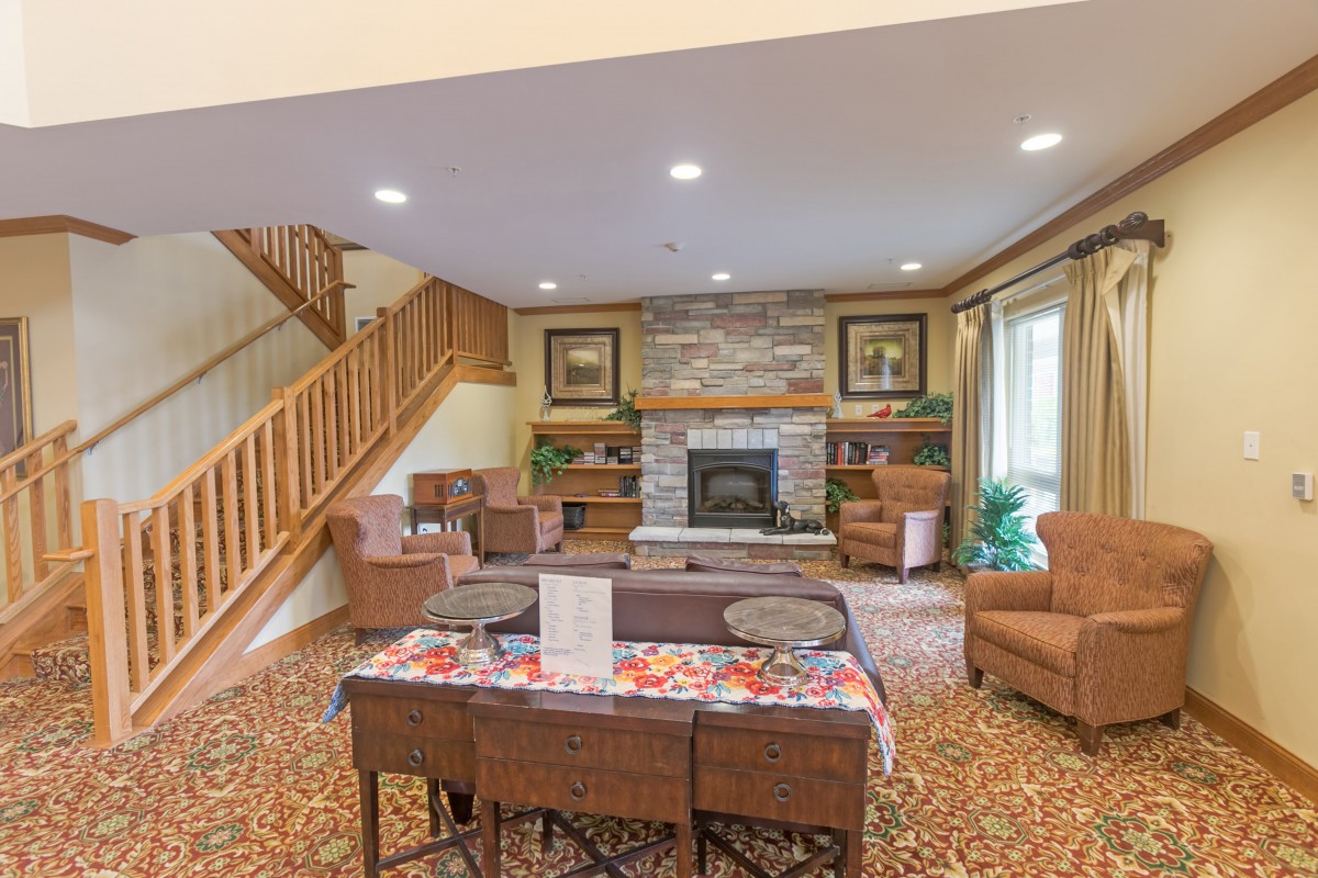 A cozy living room featuring a fireplace, comfortable seating, and a wooden staircase.