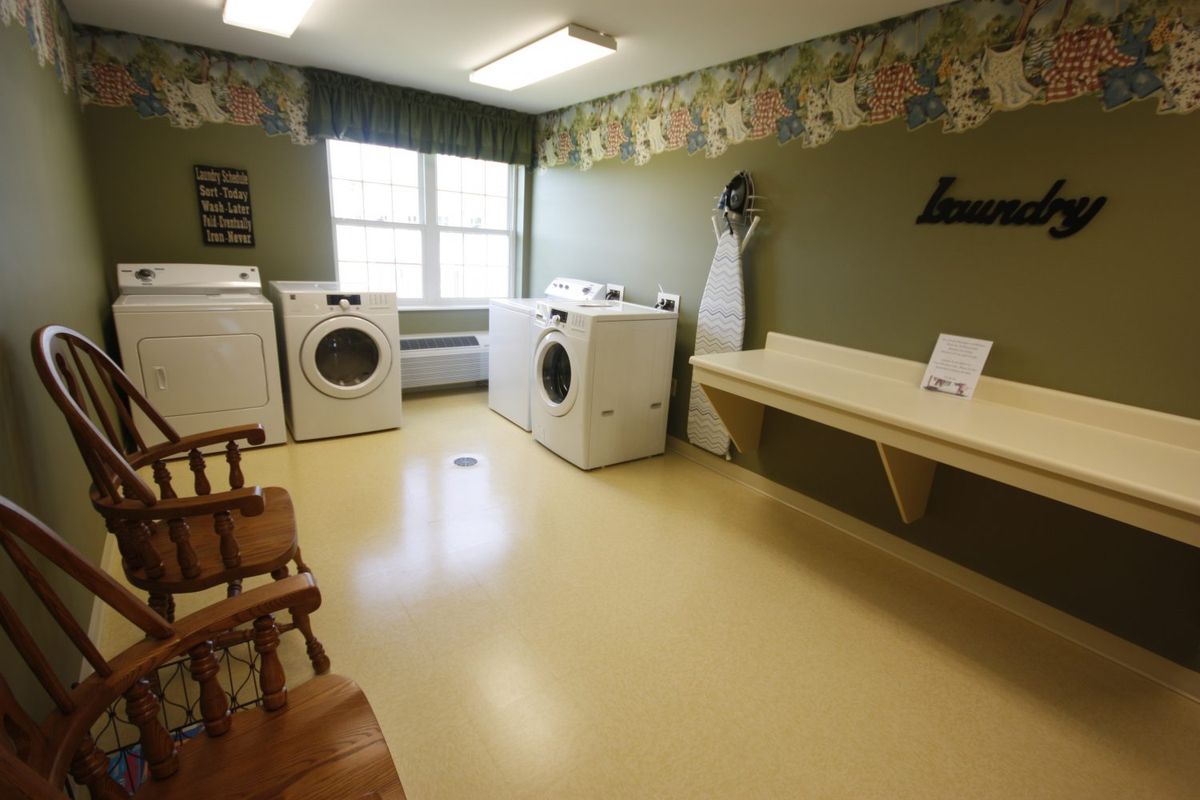 A well-organized laundry room with washing machines, a dryer, and an ironing board.