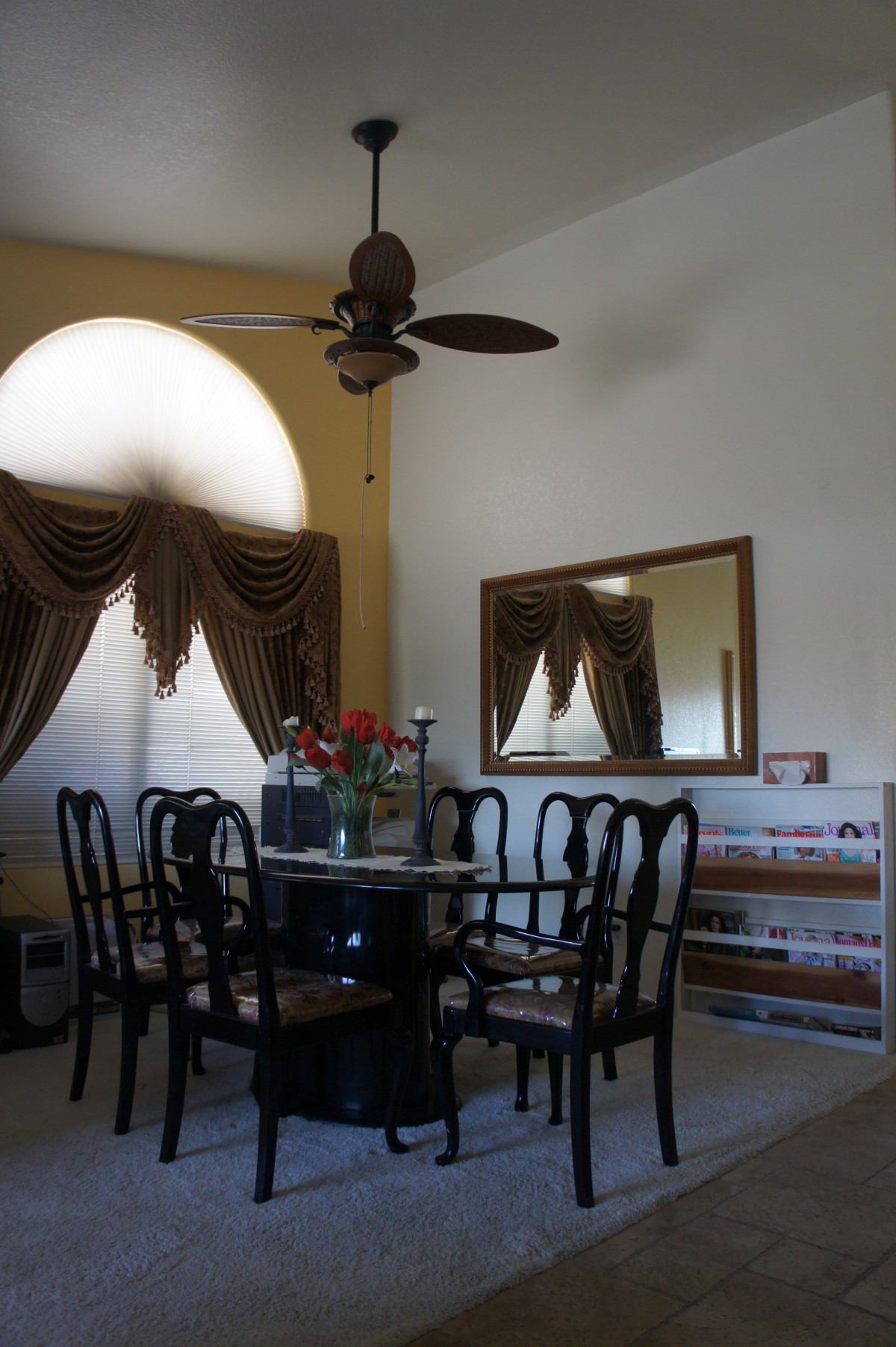 A cozy dining room with a round table, elegant chairs, and decorative curtains.