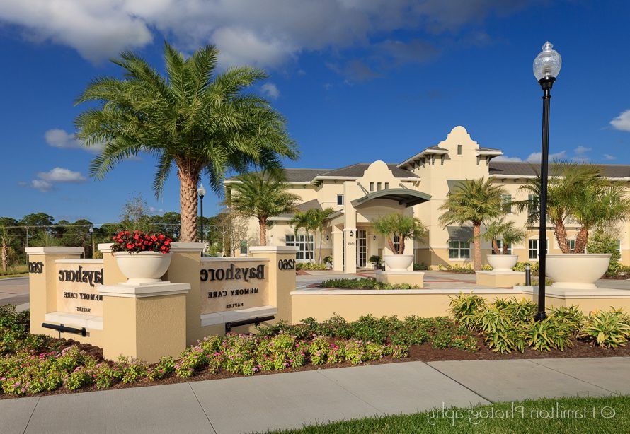 Modern residential building with palm trees and landscaped entrance.