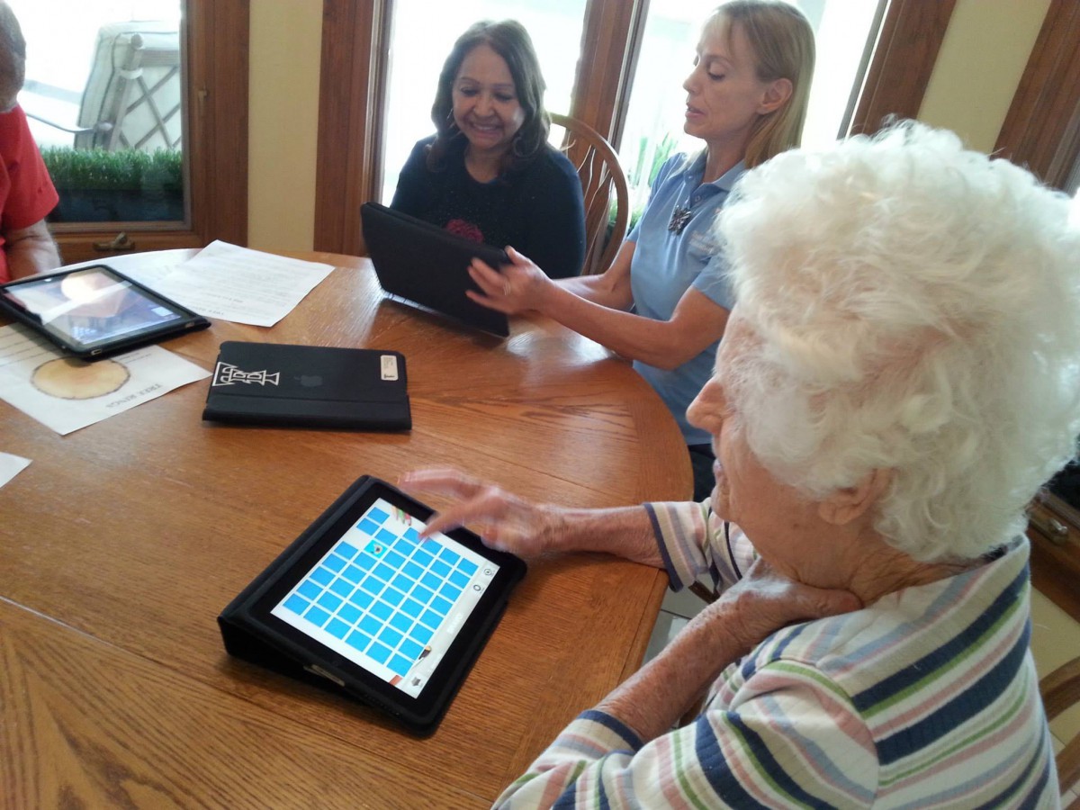 Elderly individuals engaging with technology on tablets during a learning session.
