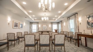 A well-lit conference room with arranged chairs facing a podium and decorative lighting.