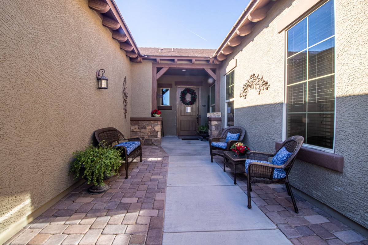A cozy outdoor patio with seating leading to a front door entrance.