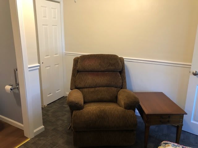 A cozy brown recliner next to a side table in a corner of the room.