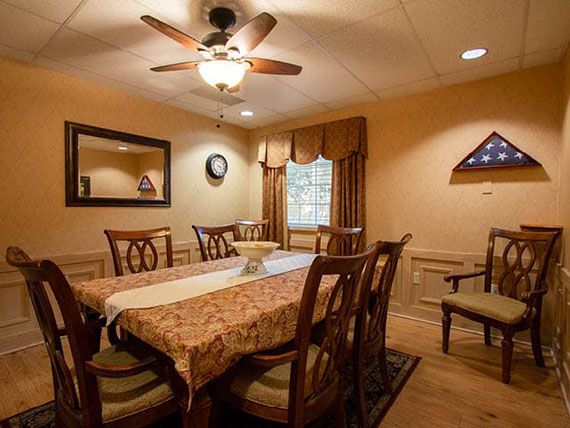 A cozy dining room with a long table, chairs, and warm lighting.