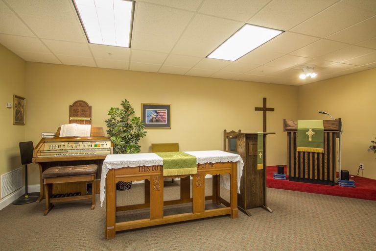 A serene chapel with an altar, cross, and seating area for worship.