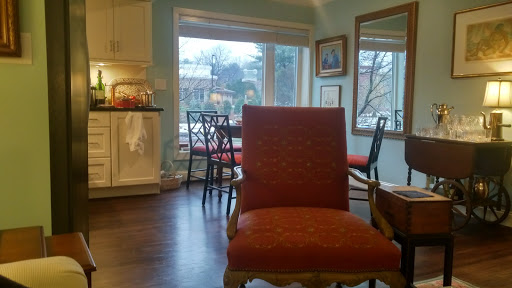 A cozy living room featuring a red upholstered chair and large windows letting in natural light.