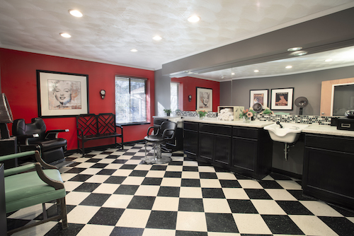 A stylish barber shop featuring a modern design with red walls and a classic black and white checkered floor.