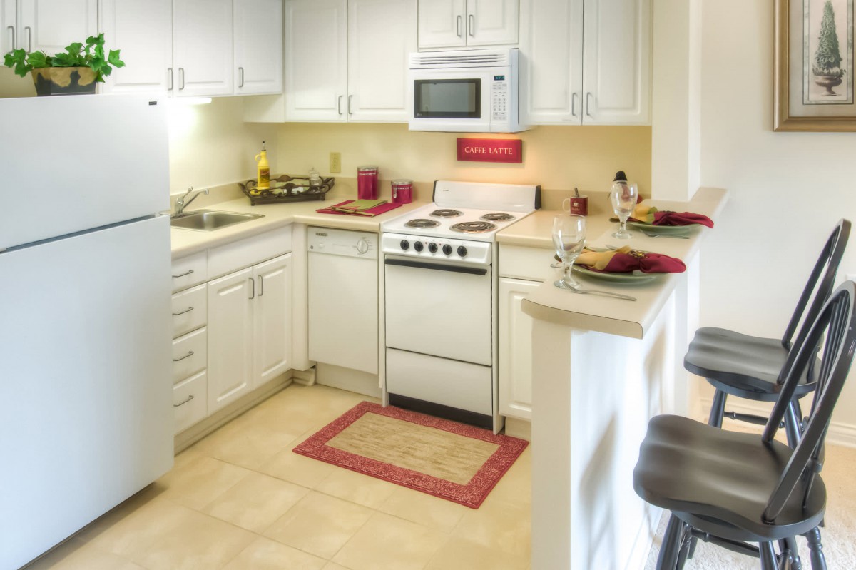 A cozy kitchen with white cabinets and modern appliances, featuring a compact oven and microwave.