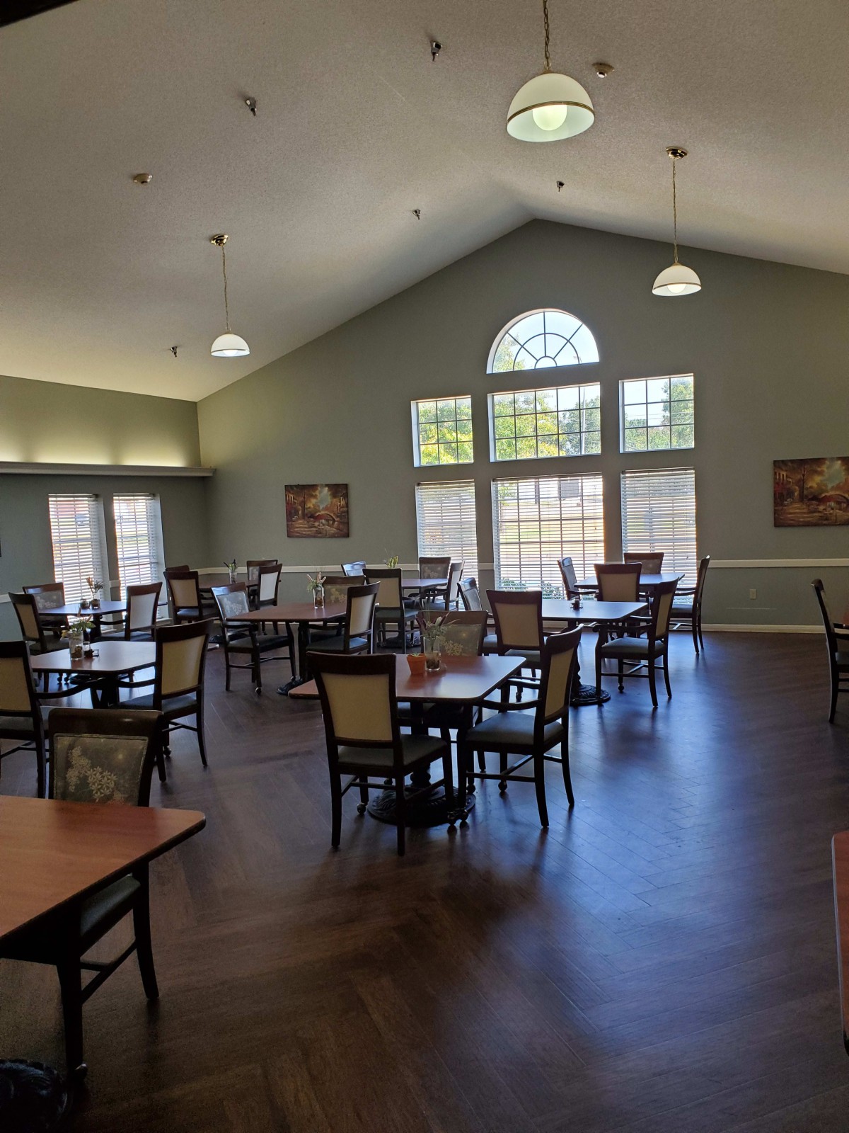 An elegant dining area with arranged tables and chairs, featuring large windows for natural lighting.