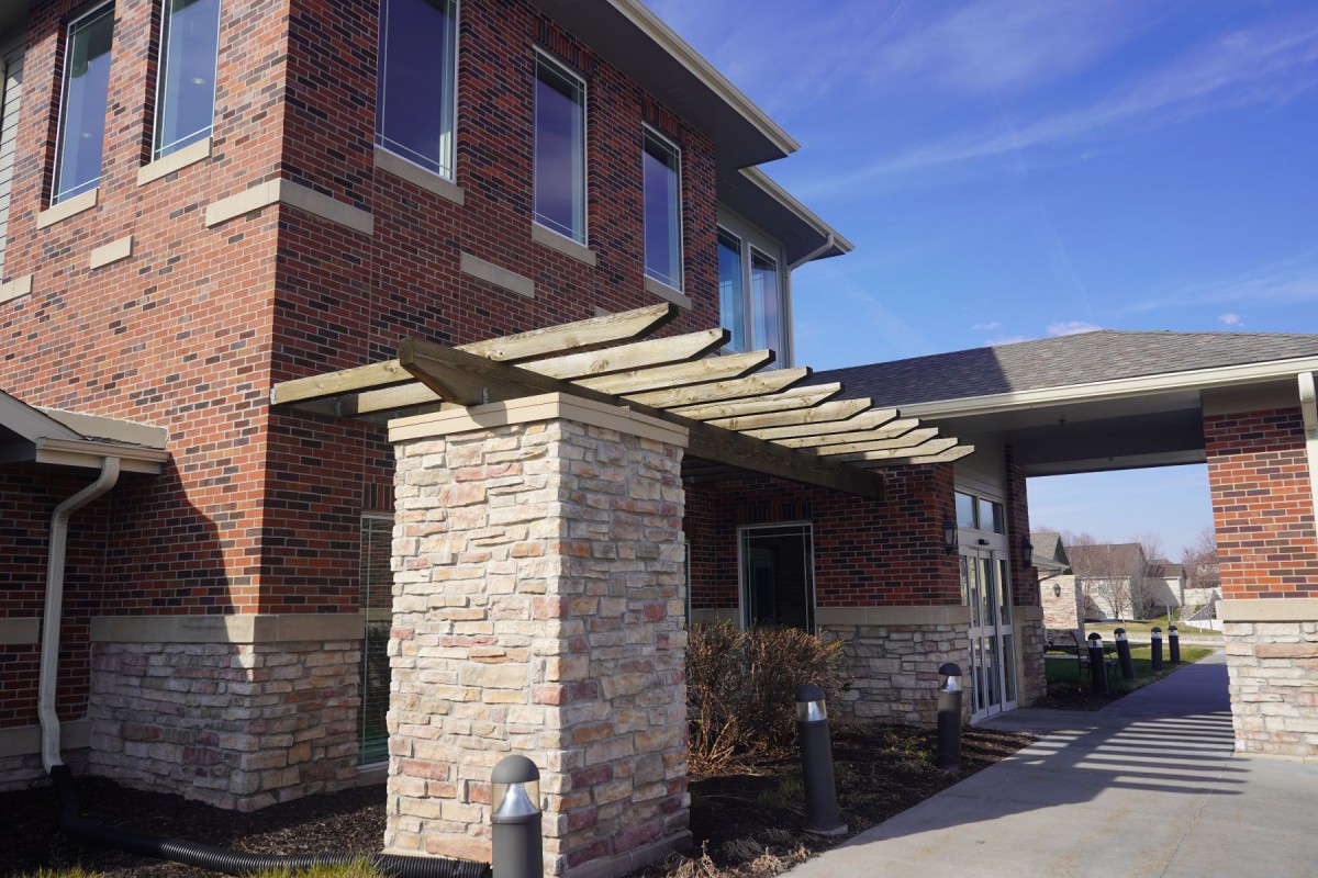A modern brick building with a stone column and canopy at the entrance.