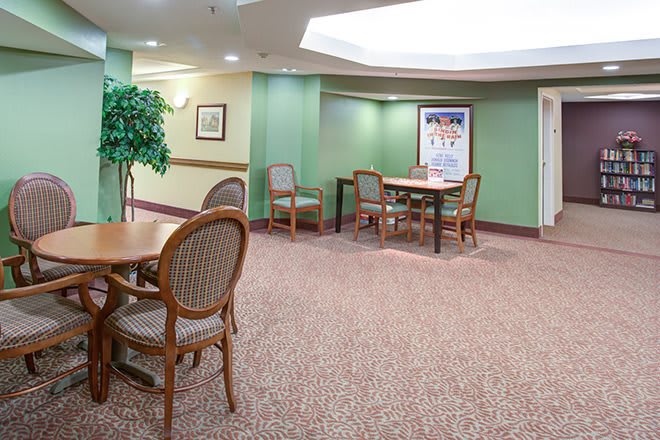 A quiet waiting area with tables, chairs, and green walls.