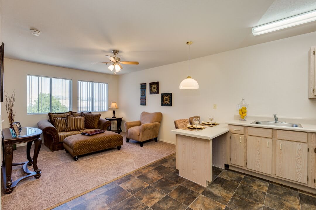 A cozy living room with a sofa, armchair, and coffee table, featuring an open floor plan with adjacent kitchen area.