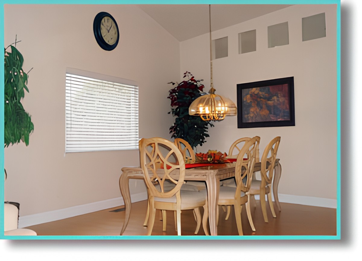 A cozy dining room with a wooden table and six chairs under a hanging chandelier.