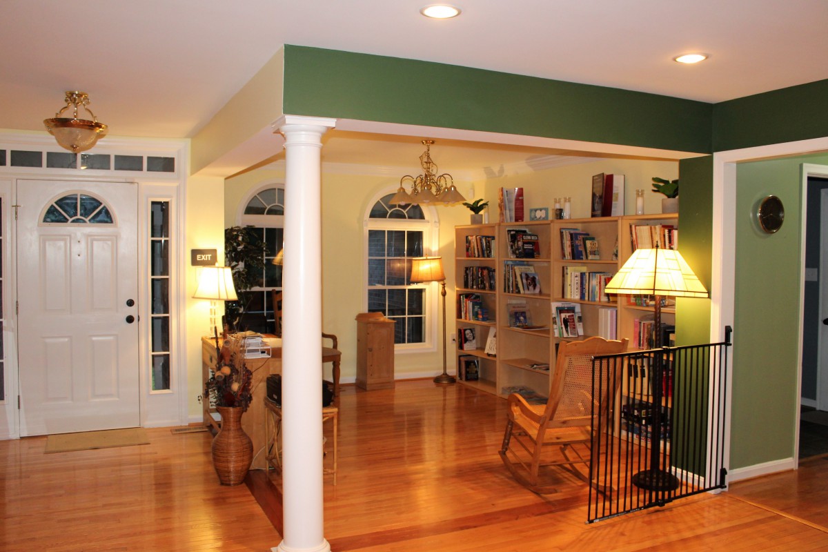 A cozy living room featuring bookshelves, wooden flooring, and warm lighting.