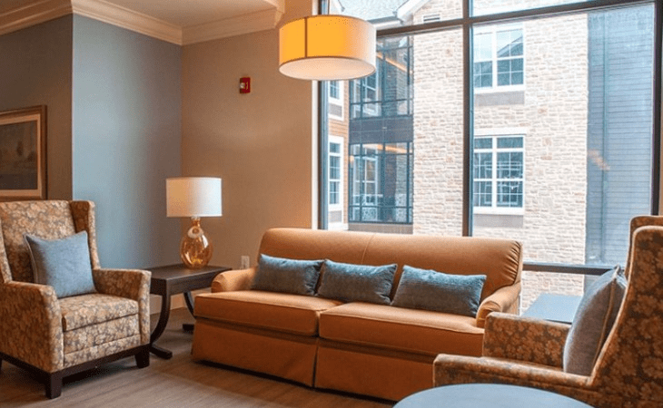 A cozy living room with a brown sofa, blue cushions, and warm lighting.