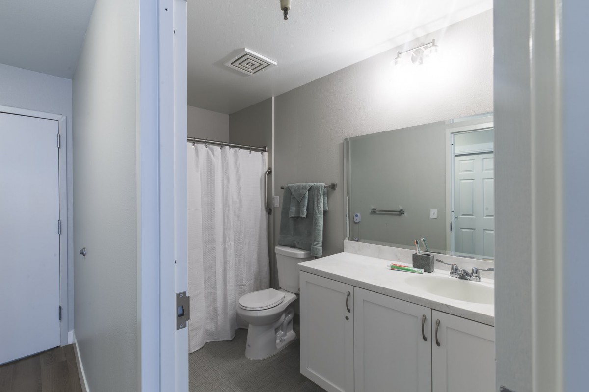 A modern bathroom with a large mirror, a white sink, and a shower area with a curtain.