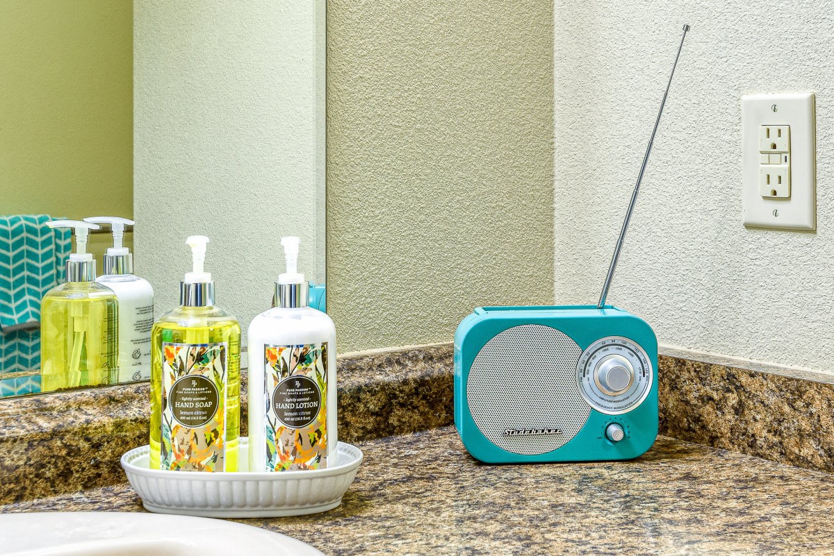 A vintage-style radio sits on a bathroom countertop beside lotions and soap.
