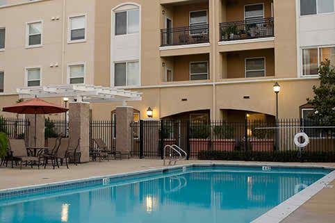 An outdoor view of an apartment complex featuring a swimming pool with balconies above.