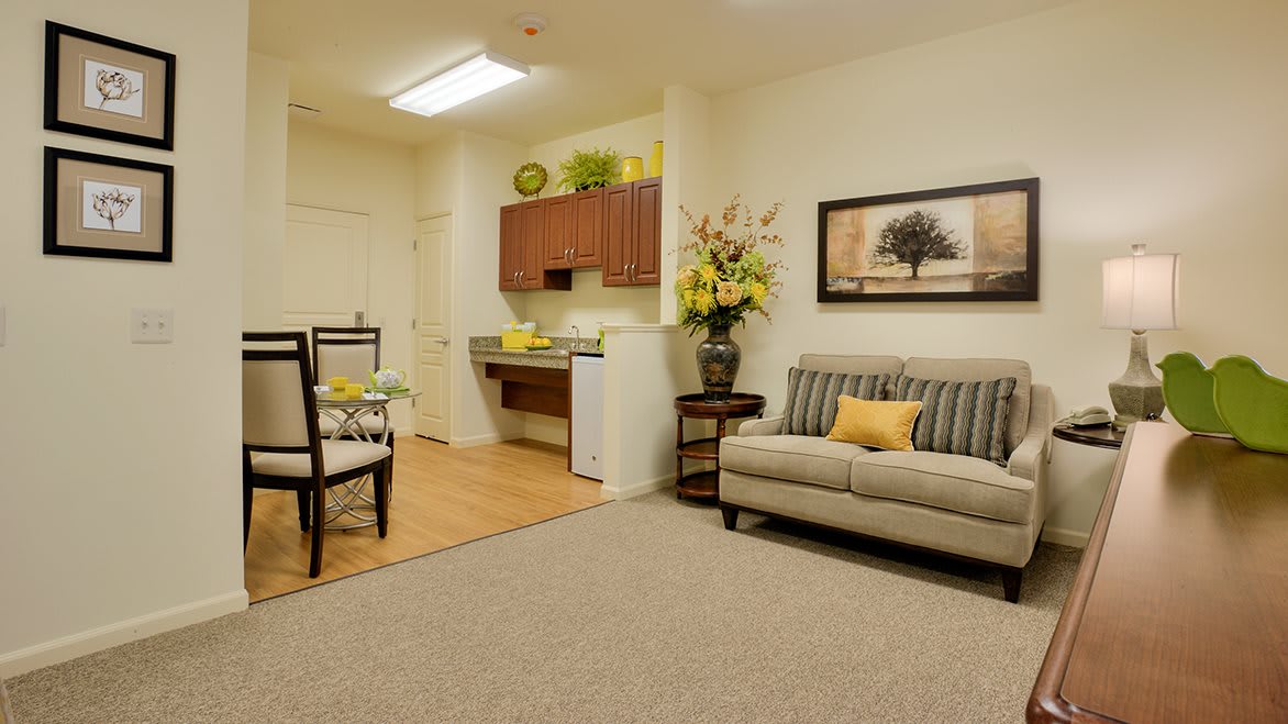 A cozy living space featuring a sofa, dining area, and kitchenette with modern decor and plants.