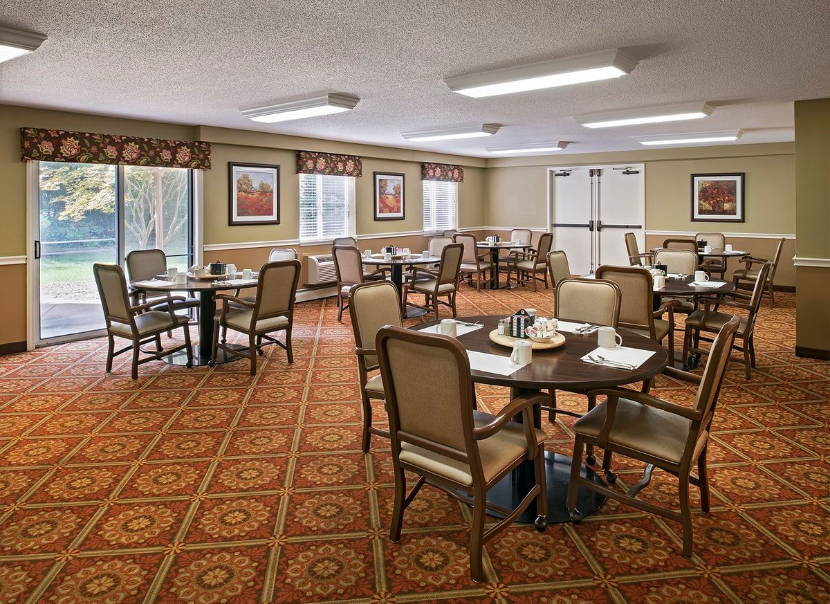 A neatly arranged dining room with tables and chairs on a patterned carpet.