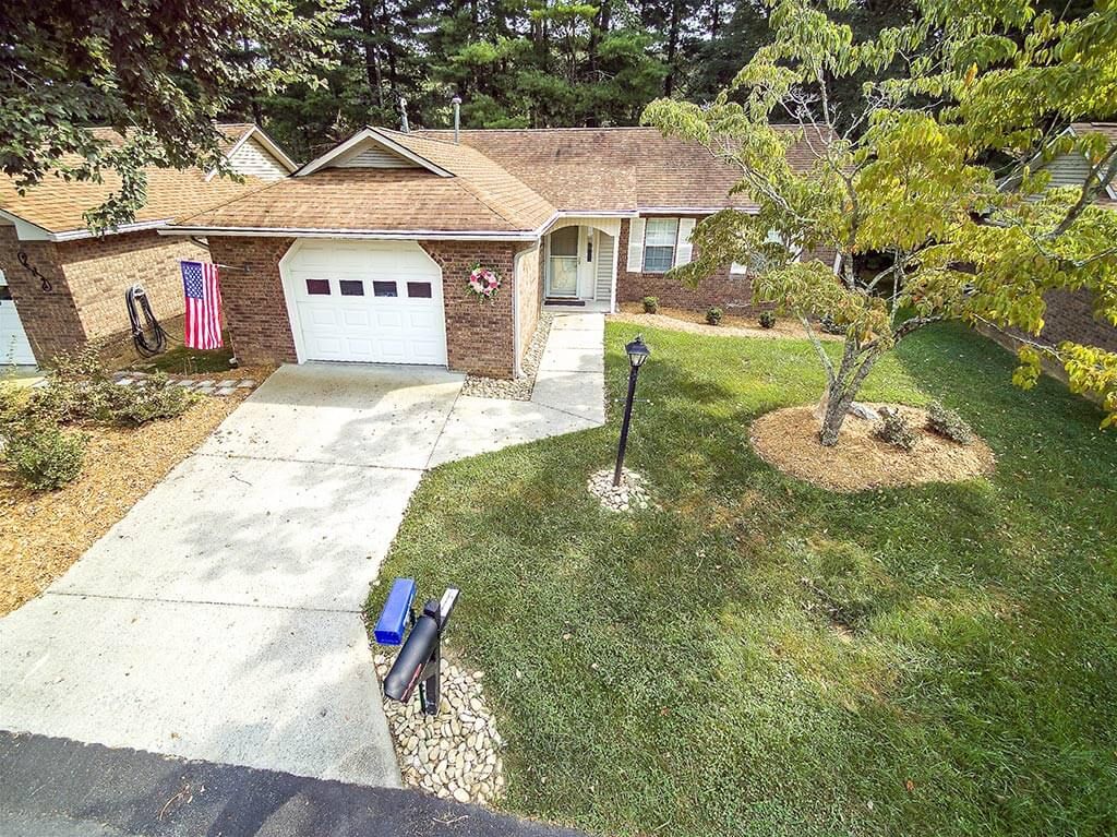 Aerial view of a suburban house with a garage and well-maintained lawn.