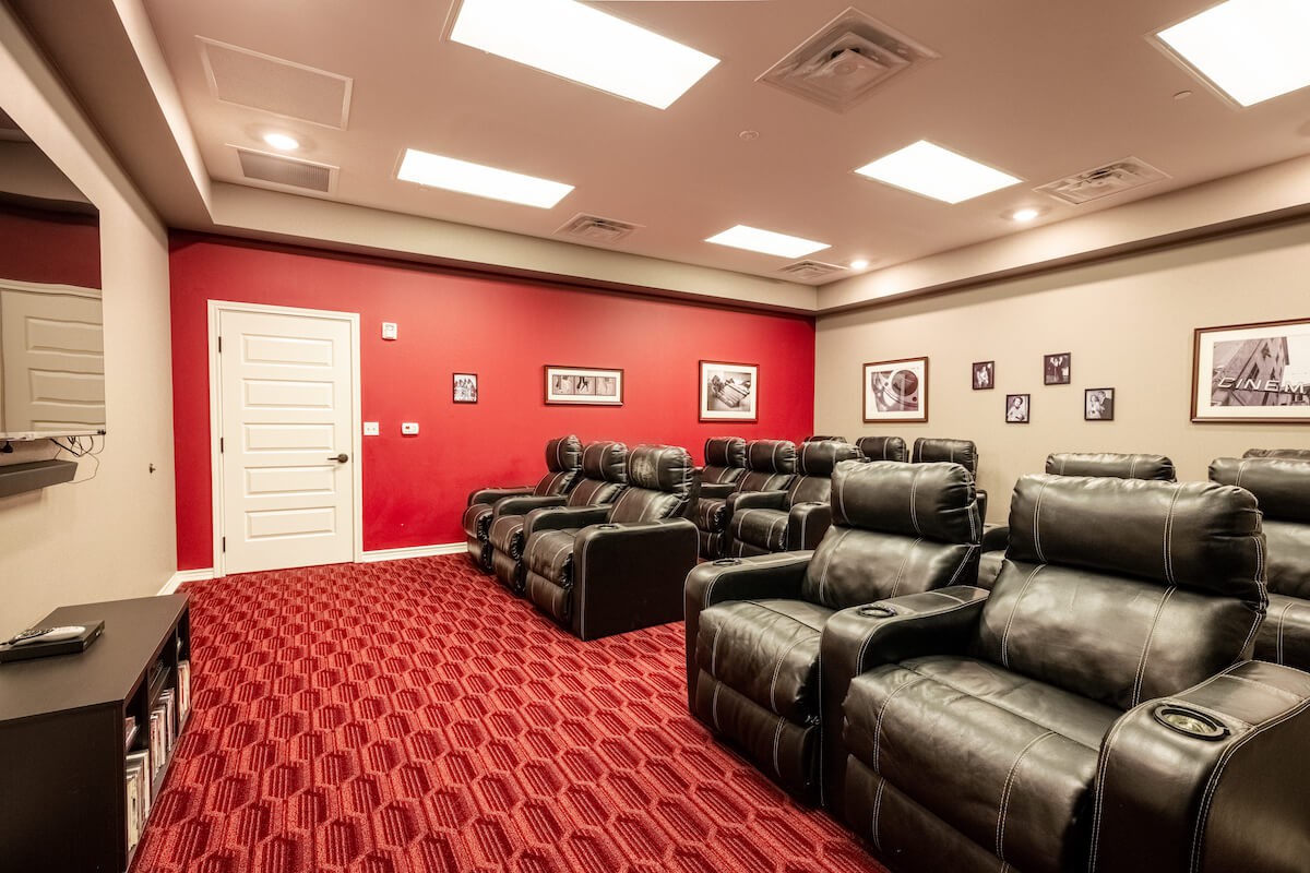 A cozy home theater room featuring comfortable recliner chairs and a vibrant red carpet.
