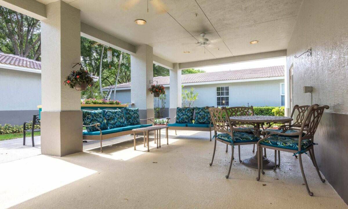 A cozy covered patio with seating and greenery.