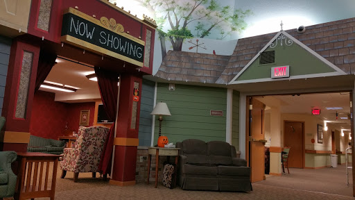 A cozy interior space resembling a theater lobby with a 'Now Showing' sign and comfortable seating.
