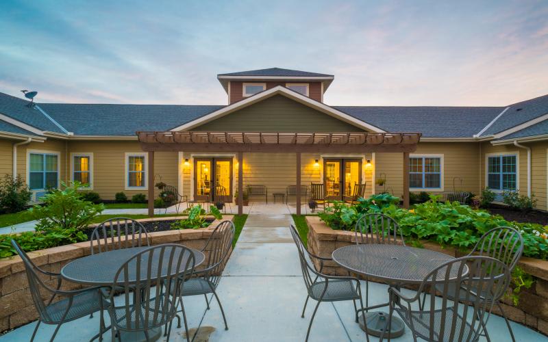 A picturesque patio area with outdoor seating in front of a residential building during the evening.