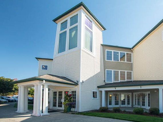 A modern residential building with large windows under a clear blue sky.
