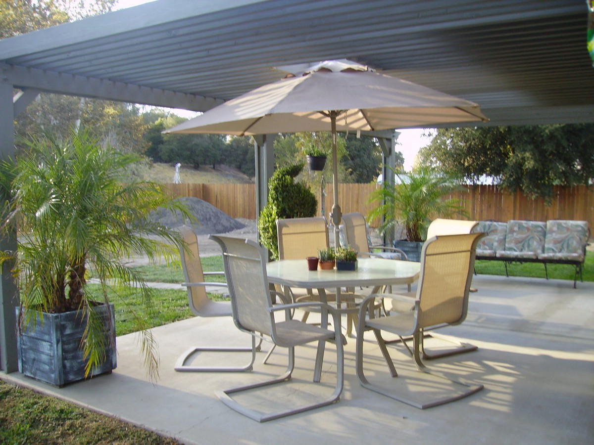 A cozy patio setup with chairs, a table, and an umbrella in a backyard setting.