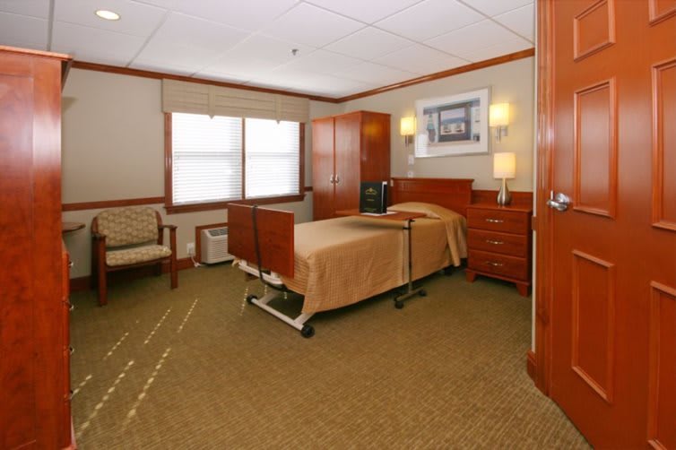 A well-furnished hospital room with a bed, cabinets, and seating area.