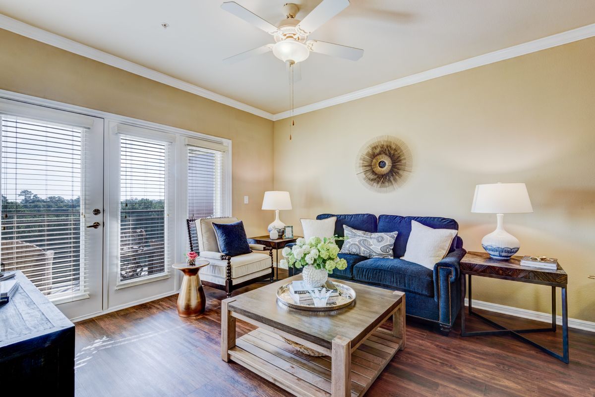 A cozy living room with a blue sofa, stylish coffee table, and warm lighting, featuring elegant decor and natural light streaming through the windows.