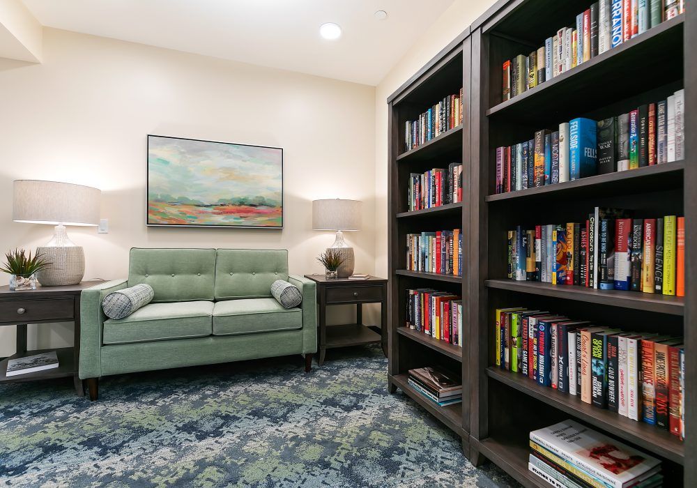 A cozy reading room with bookshelves, a comfortable sofa, and a decorative painting.
