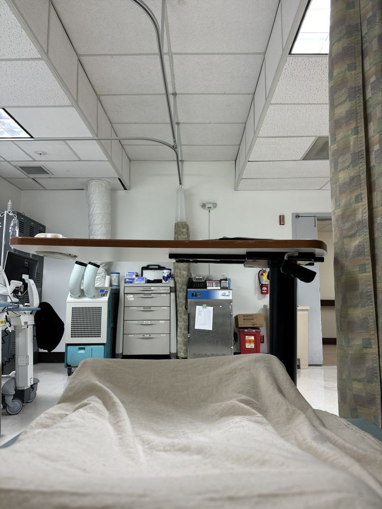 View from a hospital bed showcasing medical equipment and a curtain partition.