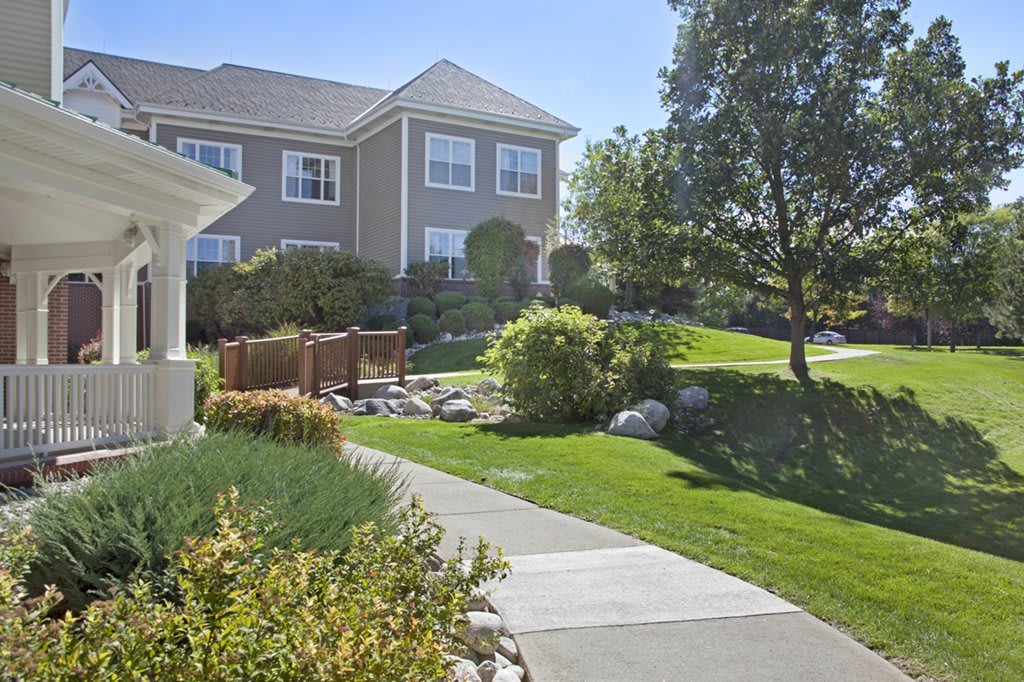 A well-maintained residential area with a house, lush garden, and a winding pathway.