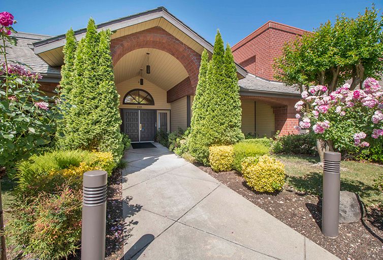 A building entrance with a landscaped pathway and surrounding greenery.