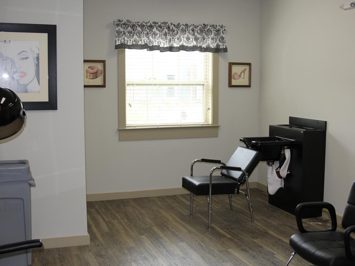 A clean and modern hair salon interior with chairs, a sink, and a large window.