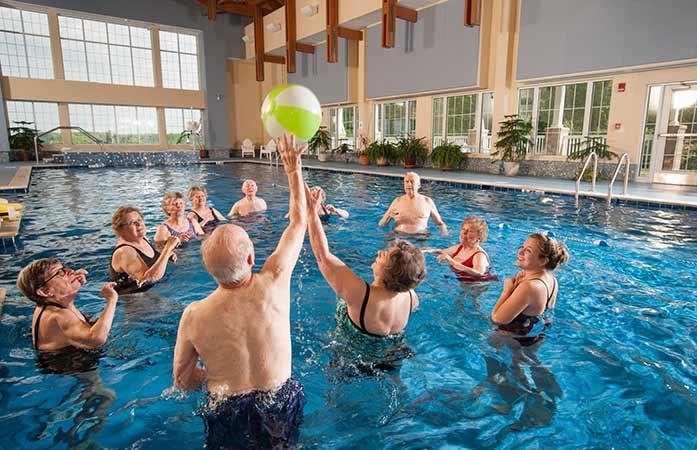 A group of seniors enjoying a water aerobics class in an indoor pool.