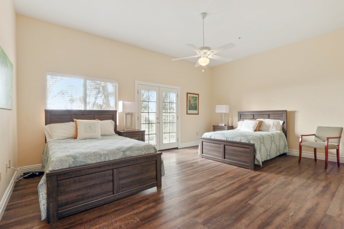 A spacious bedroom with two double beds, natural lighting, and hardwood flooring.