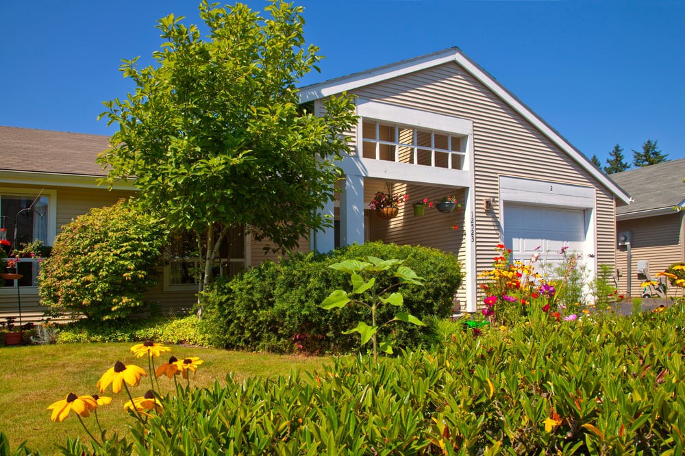 A charming house with a beautifully landscaped front yard featuring lush greenery and vibrant flowers.