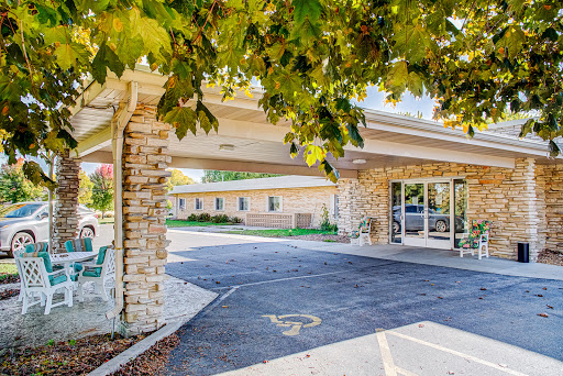 A welcoming entrance with a stone facade and canopy, surrounded by greenery.